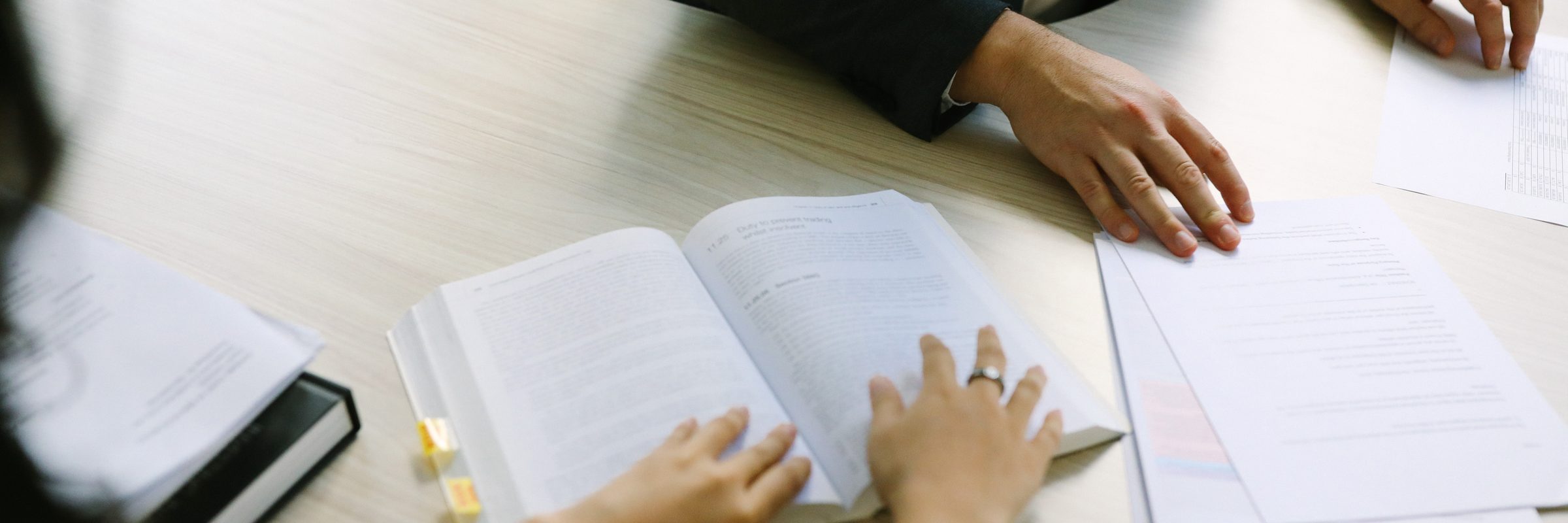 An open legal textbook and marked-up papers on a meeting table