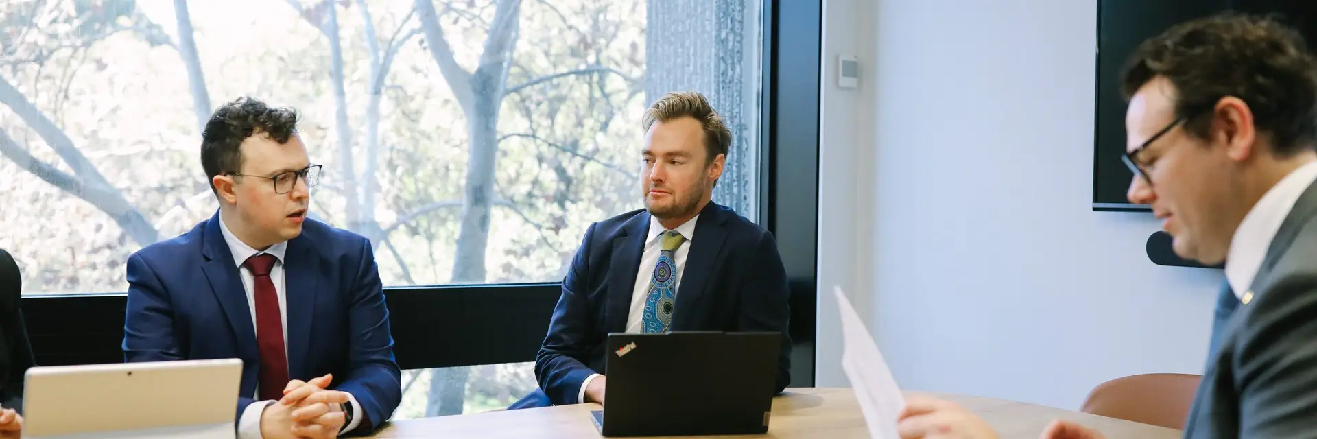 Three Boettcher Law lawyers at a meeting room table with laptops and papers