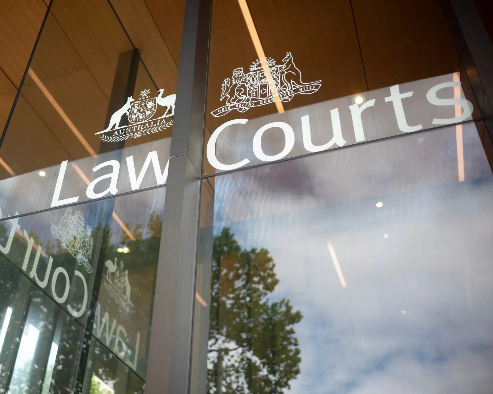 The Law Courts entrance signage in Sydney, with the Commonwealth and New South Wales coats of arms on the glass