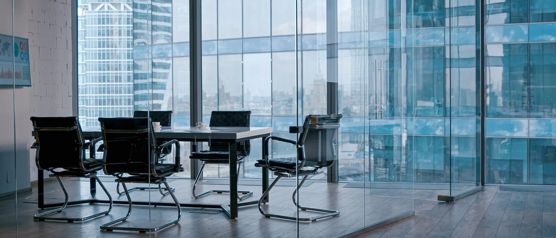 An empty boardroom with a glass wall looking out over a city