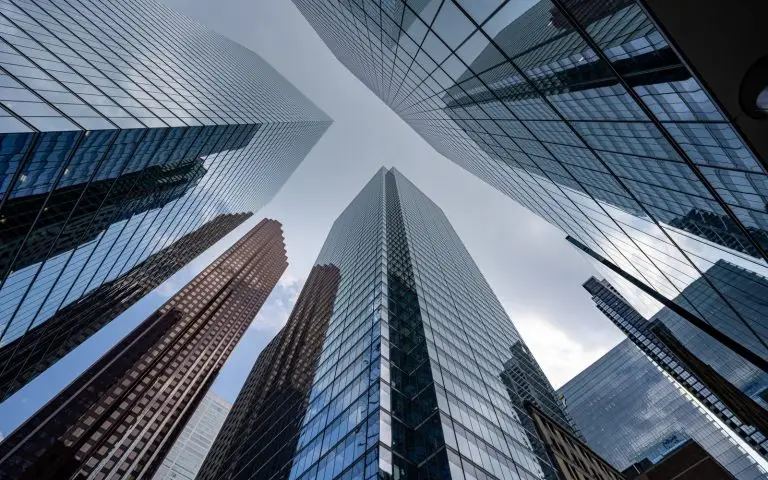 Glass office towers seen from street level, converging towards the sky
