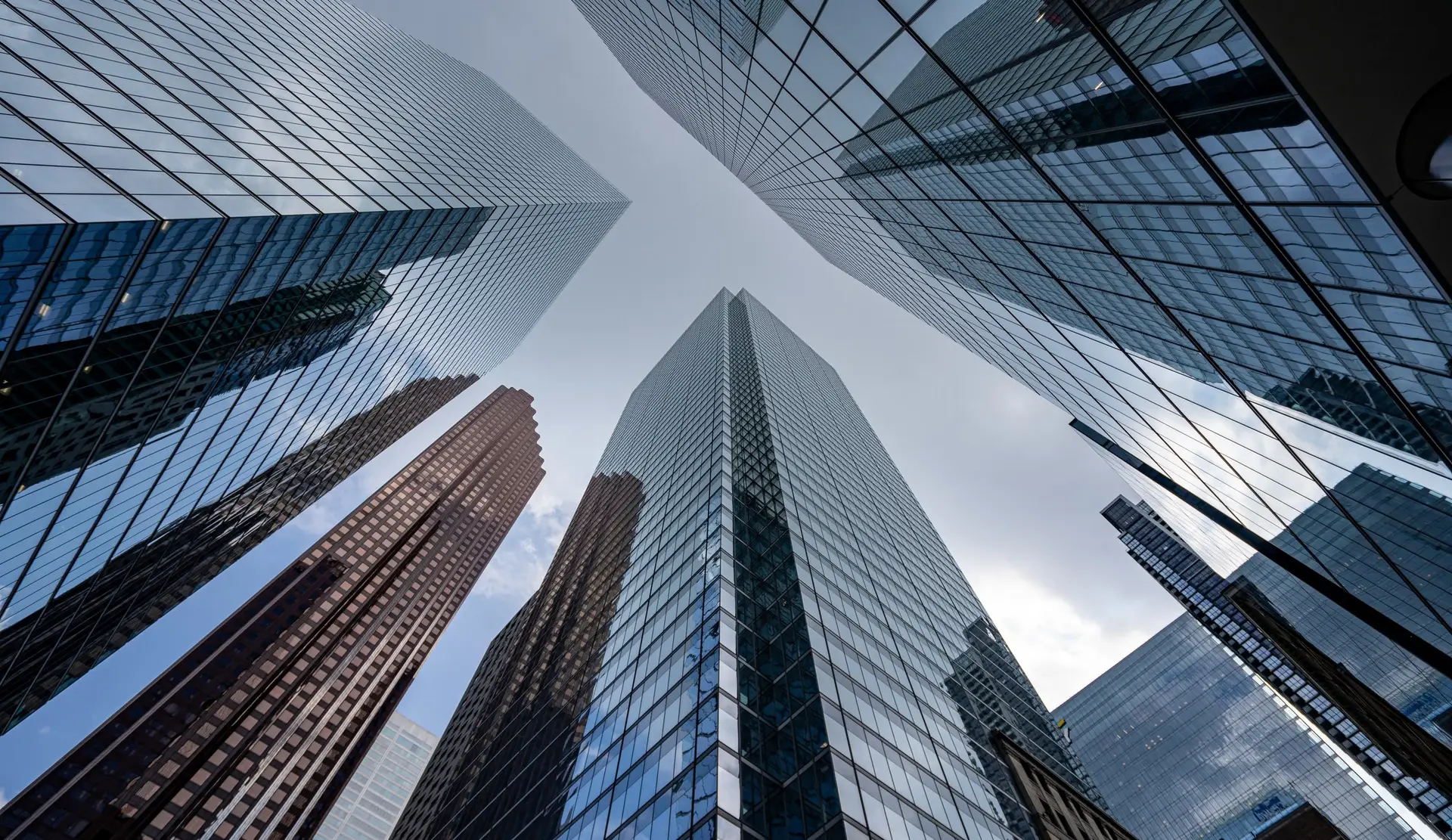 Commercial towers seen from below, glass facades converging against the sky