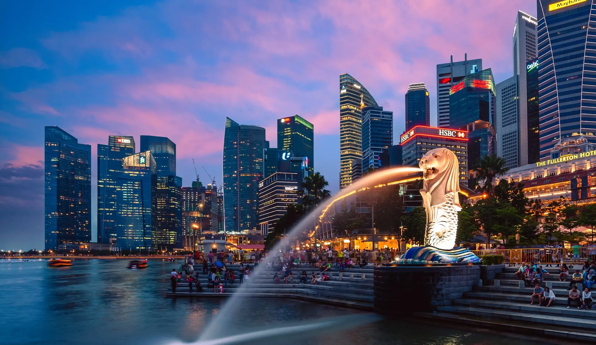 The Merlion and the Singapore central business district across Marina Bay at dusk