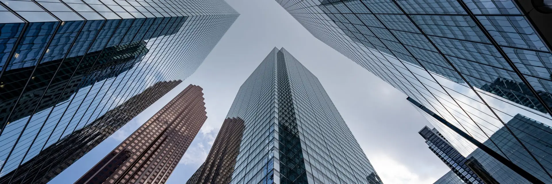 Glass towers converging upward against a clear sky