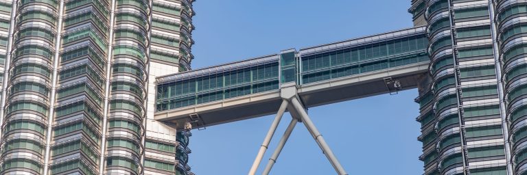Two skyscrapers joined by a double-decker skybridge against a clear sky