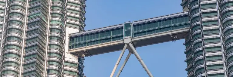 Two skyscrapers joined by a double-decker skybridge against a clear sky