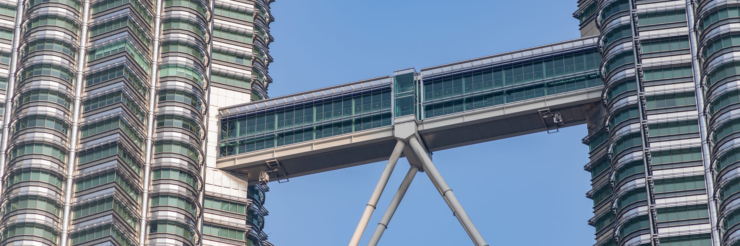 Two skyscrapers joined by a double-decker skybridge against a clear sky