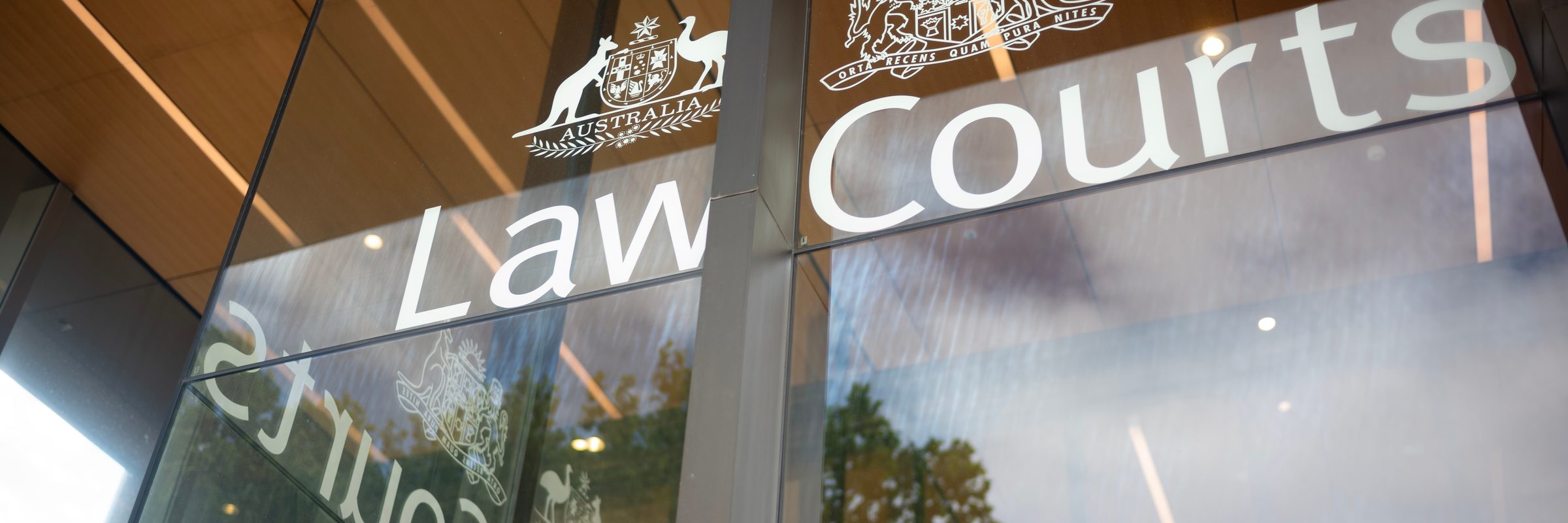 Law Courts entrance signage in Sydney, with the Commonwealth and New South Wales coats of arms etched on glass