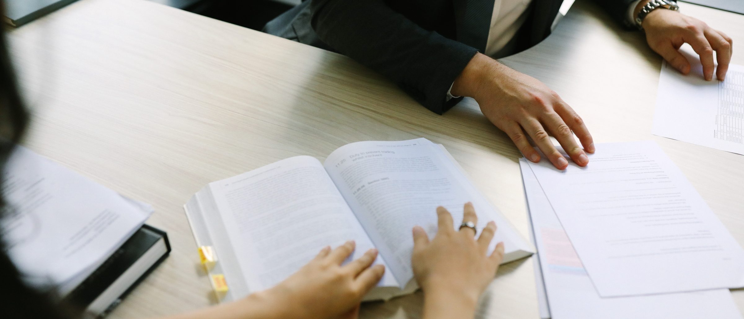 A legal textbook open beside a stack of papers on a desk