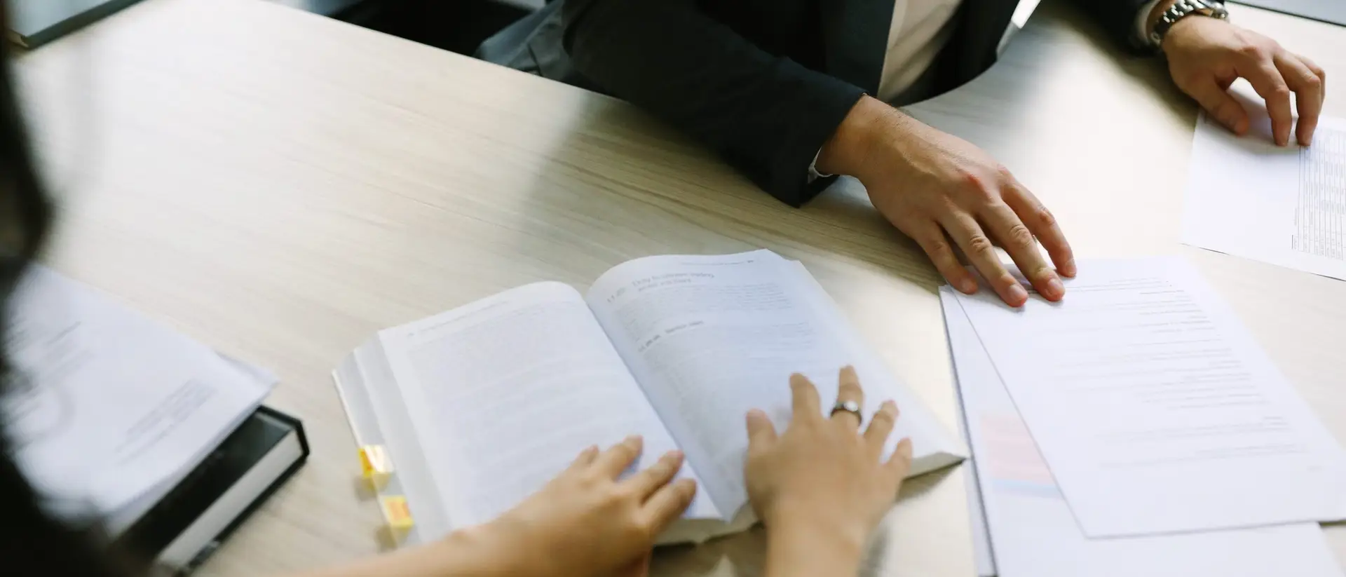 A legal textbook open beside a stack of papers on a desk