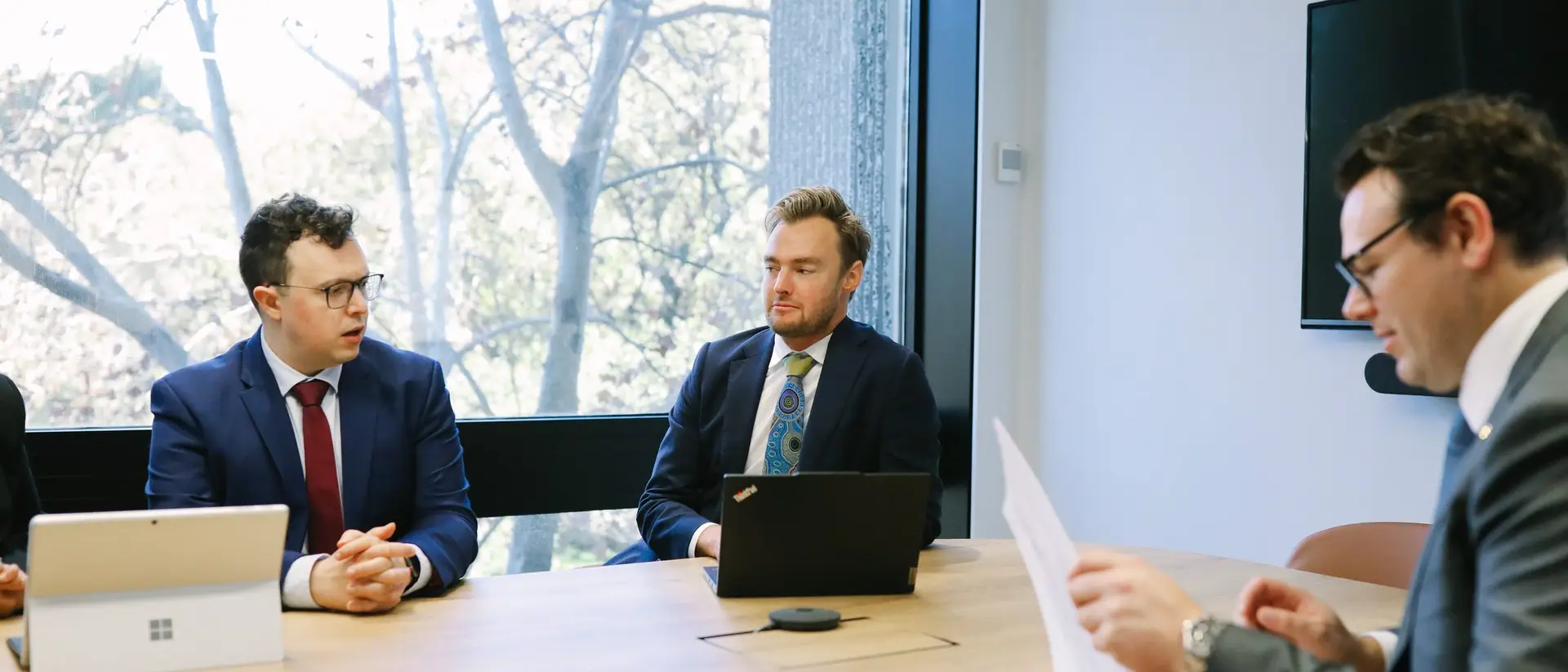 Three people around a meeting room table, the setting a mediation is prepared for