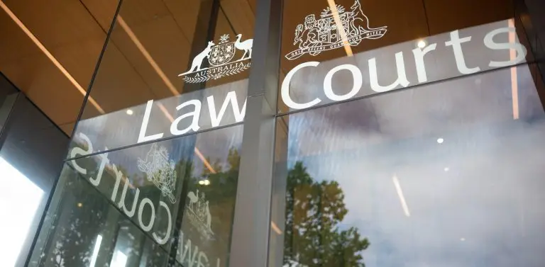 The Law Courts entrance signage in Sydney, with the Commonwealth and New South Wales coats of arms on the glass