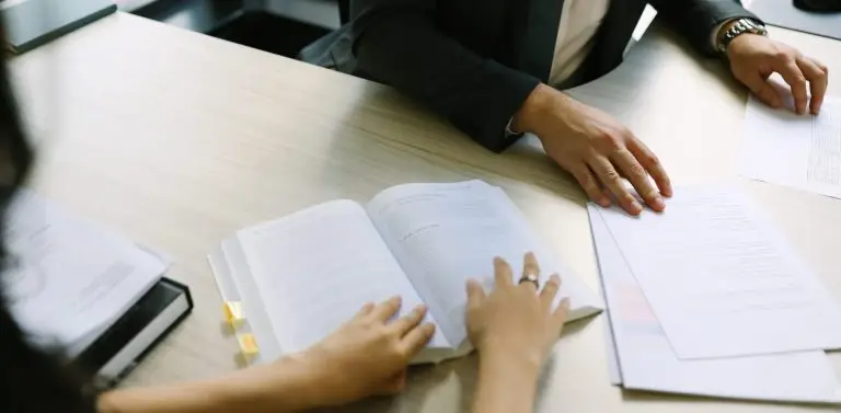 An open legal textbook and marked-up papers on a meeting table